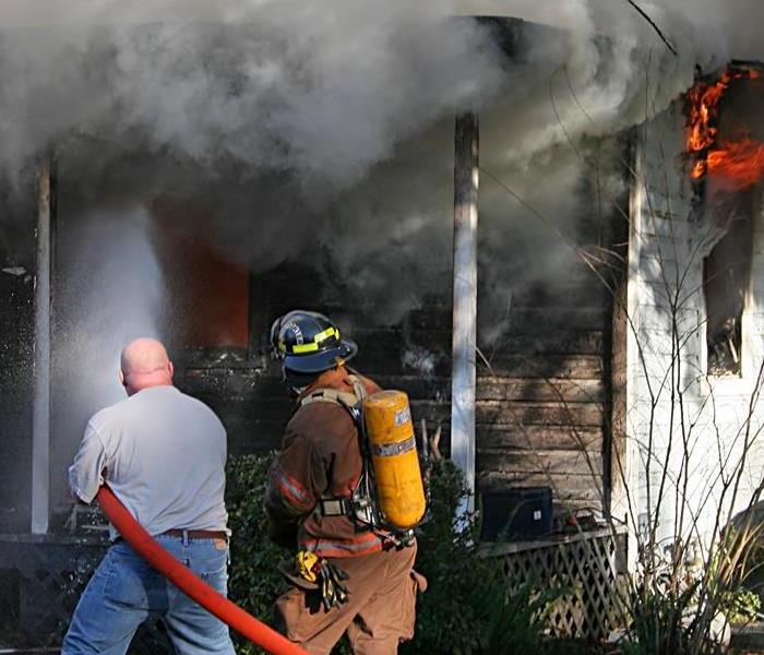 firefighters watering down a house fire